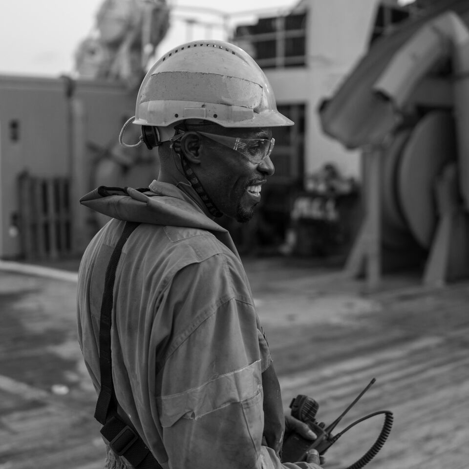 SINGLE-IMAGE_black-male-on-ship-deck-smiling-black-and-white_jul24