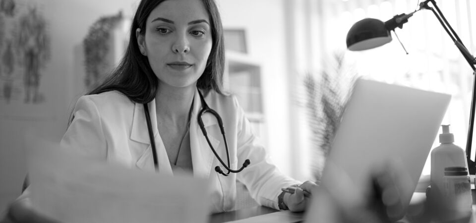 SINGLE-IMAGE_doctor-checking-paperwork-and-laptop_aug25