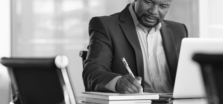 SINGLE-IMAGE_man-with-pen-and-books-at-desk_feb24