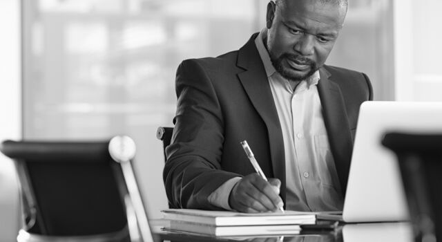SINGLE-IMAGE_man-with-pen-and-books-at-desk_feb24